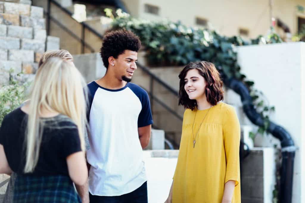 Group of three late teen friends hanging out in front of an apartment complex