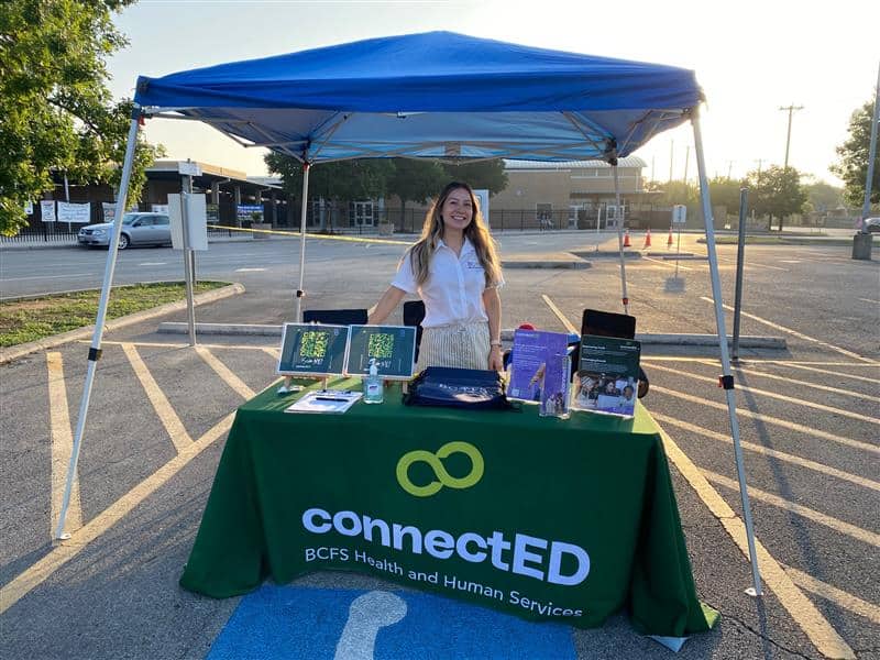 ConnectED team member sitting behind a table with outreach materials